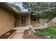 Front porch with brick facade and metal security door accented by a mature tree and manicured landscaping at 3722 Monterey Pl, Boulder, CO 80301