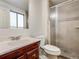 Bathroom featuring a vanity sink with dark cabinets, a toilet, and a tiled shower with glass doors at 13561 W Alaska Pl, Lakewood, CO 80228