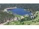 Scenic aerial view of a vast lake surrounded by lush greenery, golf course, and residential area at 30094 Upper Bear Creek Rd, Evergreen, CO 80439