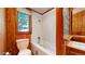Wood-paneled bathroom featuring a white-tiled tub and shower with a view to the outside at 30094 Upper Bear Creek Rd, Evergreen, CO 80439