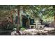 Charming log cabin with stone accents and an outdoor seating area, nestled among mature trees at 30094 Upper Bear Creek Rd, Evergreen, CO 80439