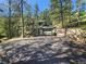 Exterior of log cabin with attached garage and large driveway, all surrounded by mature trees at 30094 Upper Bear Creek Rd, Evergreen, CO 80439