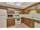A compact kitchen features oak cabinets, white appliances, and ample storage at 13800 E Marina Dr # 112, Aurora, CO 80014