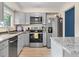 Bright kitchen featuring stainless steel appliances, gray cabinets, and granite countertops at 6856 S Broadway, Centennial, CO 80122