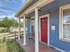Charming front porch with white columns, a red front door and a bench provides a cozy entrance to the home at 66 E 45Th Ave, Denver, CO 80216
