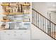 A modern wet bar area featuring open shelving, a tiled backsplash, white cabinets, and an adjacent staircase at 2679 Leafdale Cir, Castle Rock, CO 80109