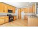 Open kitchen features wood cabinets, granite countertops, stainless appliances, and hardwood floors at 21286 E Nassau Ave, Aurora, CO 80013