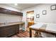 A well-organized kitchenette featuring dark wood cabinets, a sink and table, and bathroom access at 21286 E Nassau Ave, Aurora, CO 80013