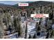 Aerial view of the subject property surrounded by mature trees and adjacent land at 10438 Sunlight Ln, Conifer, CO 80433
