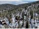 An aerial view of the property surrounded by tall evergreens and a beautiful mountain landscape at 10438 Sunlight Ln, Conifer, CO 80433
