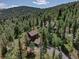 Aerial view of a wooded property featuring a charming home nestled among lush green trees with a long driveway at 10438 Sunlight Ln, Conifer, CO 80433