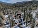 Aerial view of the home nestled in a forested area with a long driveway and surrounding mountains at 10438 Sunlight Ln, Conifer, CO 80433