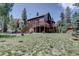 Exterior of this home with a wooden deck, lawn, and lots of trees at 10438 Sunlight Ln, Conifer, CO 80433
