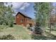 Exterior of this home with a wooden deck, lawn, and lots of mature trees at 10438 Sunlight Ln, Conifer, CO 80433