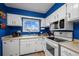 Well-lit kitchen features bright blue walls, white cabinetry, and a window over the sink at 6930 S Broadway, Centennial, CO 80122