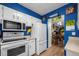 Modern kitchen featuring bright blue walls, white cabinetry and appliances at 6930 S Broadway, Centennial, CO 80122