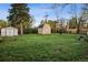 Expansive backyard with a well-maintained lawn, storage sheds, mature trees, and privacy fencing at 6390 W 47Th Ave, Wheat Ridge, CO 80033