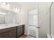 Bathroom features a dual sink vanity, white walls and trim, and a view into the next room at 9313 Biscay St, Commerce City, CO 80022