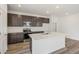 Modern kitchen features stainless steel appliances, dark cabinets, and a large island with quartz countertops at 9313 Biscay St, Commerce City, CO 80022