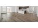 Open-concept living room featuring hardwood floors, kitchen with island, and abundant natural light at 9313 Biscay St, Commerce City, CO 80022