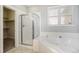 Bright bathroom featuring a separate glass enclosed shower and large soaking tub with tile surround and ample natural light at 19232 E Adriatic Pl, Aurora, CO 80013