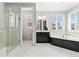 Bright primary bathroom featuring double windows with plantation shutters, a soaking tub, and a glass shower at 6728 S Catawba Way, Aurora, CO 80016