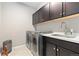 Laundry Room featuring modern washer and dryer units, ample storage, countertop space, and a sink at 6728 S Catawba Way, Aurora, CO 80016