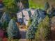 Stunning aerial view of gray two-story home surrounded by mature evergreens and lush landscaping with a brick driveway at 98 Glenmoor Ln, Cherry Hills Village, CO 80113