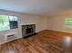Spacious living room featuring wood floors, stone fireplace, large windows, and an air conditioning unit at 17361 E Mansfield Ave # 532R, Aurora, CO 80013