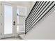 Modern entryway features a white door, sidelight window, and a sleek black railing staircase with wooden steps at 11481 E Briarwood Cir, Centennial, CO 80112