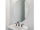 Elegant half bathroom featuring oval mirror, white fixtures, and minimalist design at 11481 E Briarwood Cir, Centennial, CO 80112