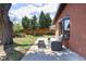 View of backyard patio and brick house, with a seating area under the shade of mature trees at 8100 W 8Th Ave, Lakewood, CO 80214