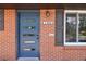 Modern blue front door with sidelight window and dark shutters on a brick house at 8100 W 8Th Ave, Lakewood, CO 80214