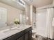 Bathroom features a dual sink vanity with gray cabinets and a shower-tub combo at 12734 E 104Th Pl, Commerce City, CO 80022