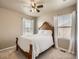 Bright bedroom with a wooden bed frame, white bedding, windows with sheer curtains, and ceiling fan at 12734 E 104Th Pl, Commerce City, CO 80022