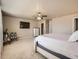 Light main bedroom showcasing a ceiling fan, television, stylish furnishings, and an ensuite door at 12734 E 104Th Pl, Commerce City, CO 80022