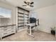 Well-lit office with a modern desk, mounted computer, built-in shelving, and a ceiling fan at 12734 E 104Th Pl, Commerce City, CO 80022