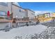 Back view of townhomes featuring private decks and snow-covered yards with a view of homes and an embankment at 909 Burning Bush Pt, Monument, CO 80132