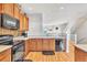 Kitchen features wood cabinets, black appliances, and a view to the adjacent living area at 909 Burning Bush Pt, Monument, CO 80132