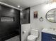 Modern bathroom featuring black tiled shower with stylish fixtures, and a sleek vanity with blue cabinetry at 6055 W Progress Ave, Littleton, CO 80123