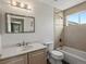 Well-lit bathroom featuring tiled shower/tub, a modern vanity with stylish countertop, and a large mirror at 6055 W Progress Ave, Littleton, CO 80123