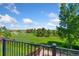 Exterior deck featuring black metal railing overlooking a grassy field with scattered trees on a sunny day at 6055 W Progress Ave, Littleton, CO 80123
