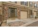 Tan three-story townhome with stone accents, attached garage, and landscaping at 985 Burning Bush Pt, Monument, CO 80132