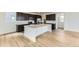 Modern kitchen featuring dark cabinetry, stainless steel appliances, an island, and wood-look flooring at 8867 Waterleaf Ln, Littleton, CO 80125