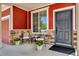 Inviting front porch with chairs, plants, stone accents and red siding creates a cozy entrance at 5558 Malta St, Denver, CO 80249