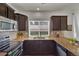 Modern kitchen with dark cabinetry, stainless steel appliances, granite countertops, and tile backsplash at 5558 Malta St, Denver, CO 80249