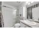 This all-white bathroom has tiled walls, glass shower door, and a cabinet above the toilet for extra storage at 5280 Genoa St, Denver, CO 80249