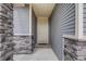 Close-up of a charming front door with stone accents and light gray siding at 5280 Genoa St, Denver, CO 80249
