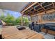 Inviting outdoor kitchen features a built-in grill, bar seating, dining area, and stylish pergola with decorative shade at 5280 Genoa St, Denver, CO 80249