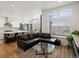 Open-concept living room and kitchen featuring a black leather sofa and large windows at 5469 S Curtice St # E, Littleton, CO 80120